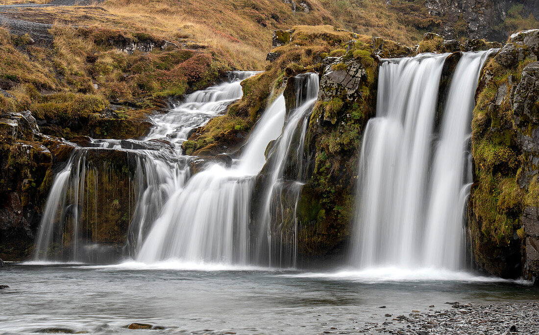 Wasserfälle, die über die Klippen in der zerklüfteten Landschaft stürzen; Island