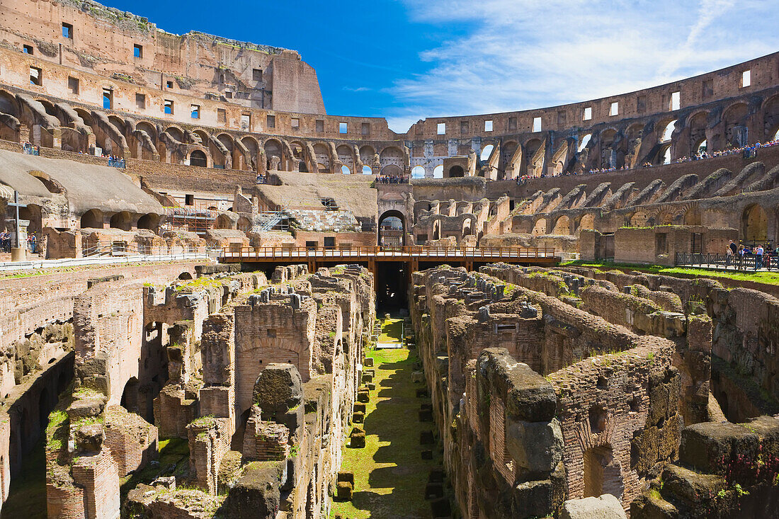 Blick durch die unterirdischen Tunnel und das unterirdische Stockwerk des Kolosseums mit blauem Himmel und Touristengruppen bei der Besichtigung; Rom, Latium, Italien