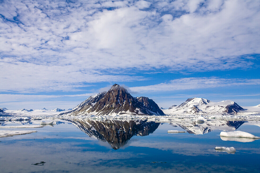 Zackige Küstengipfel, die sich im kalten arktischen Wasser spiegeln.