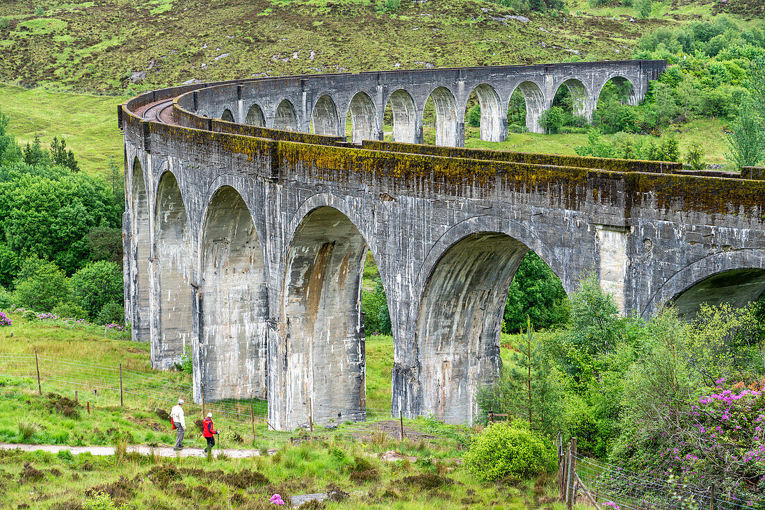 Two hikers walk toward the viaduct at Glenfinnan, Scotland; Glenfinnan, Inverness-shire, Scotland