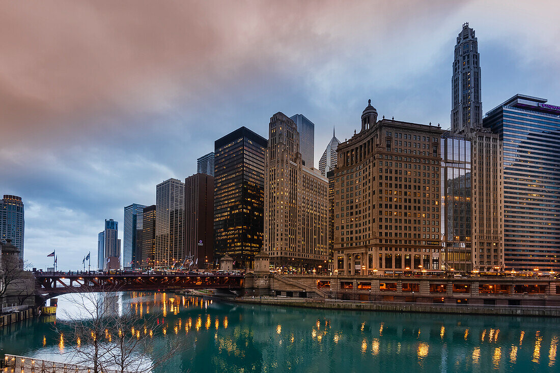 Blick auf den Chicago River und die DuSable Bridge mit einem Stadtbild aus ikonischen Bürotürmen, darunter 333 North Michigan, das London Guarantee Building und der Mather Tower, in der Stadt Chicago an einem regnerischen Abend; Chicago, Cook County, Illinois, Vereinigte Staaten von Amerika