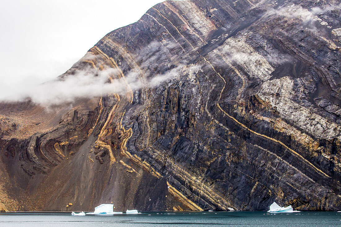 Seaside mountain with visible sedimentary layers.