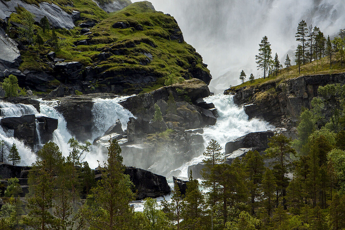 Flow from the bottom of a waterfall pours over a rocky landscape.