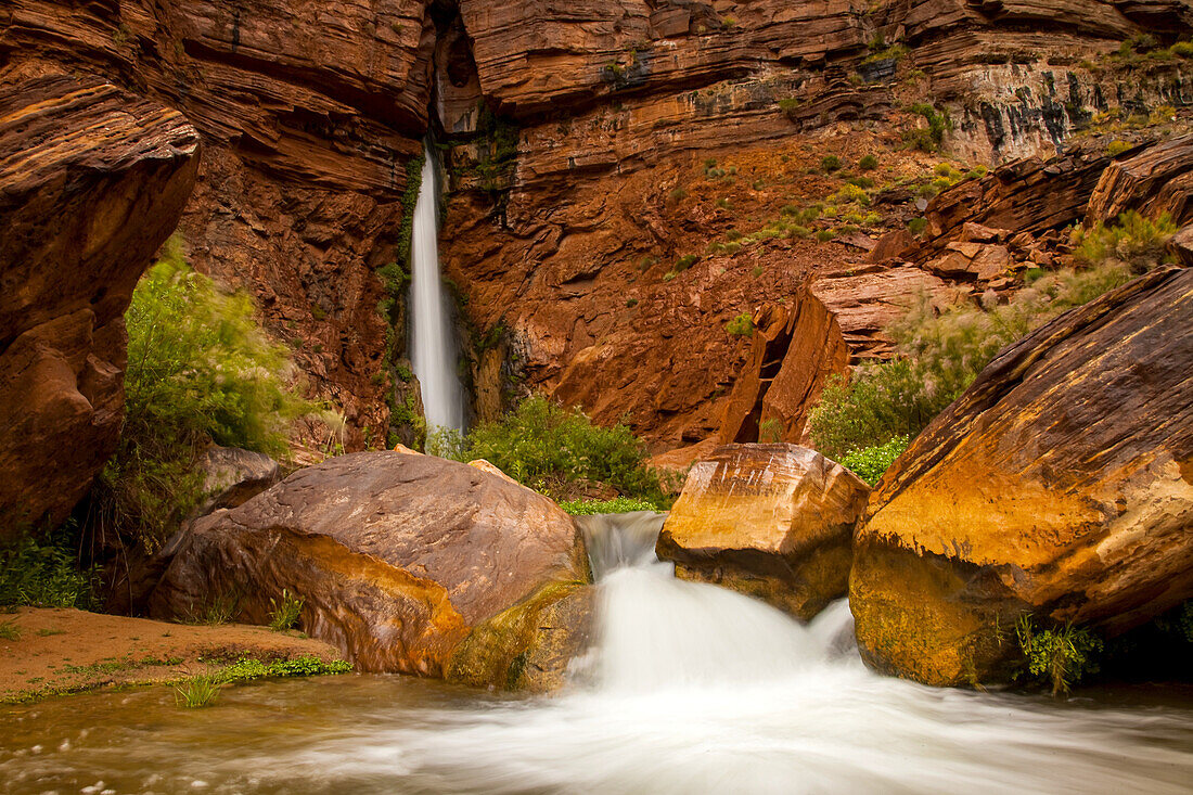 Wasserfall aus einer schmalen Felsspalte in einem Sandsteinfelsen.