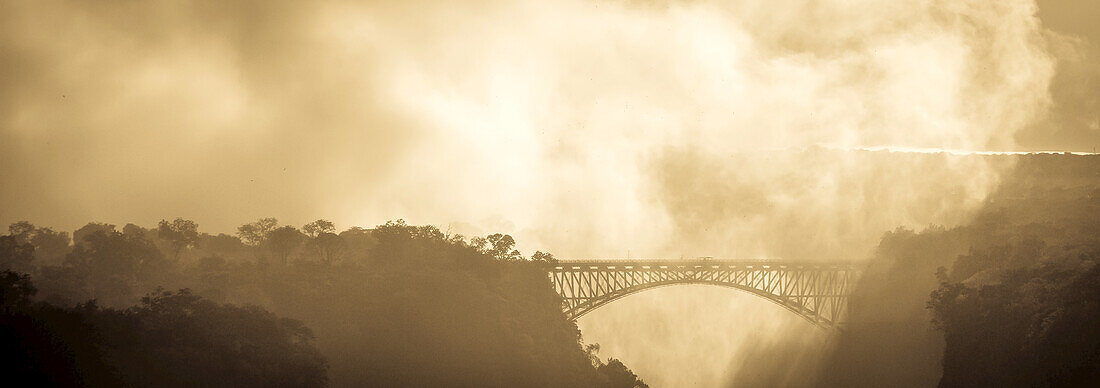 Mist from a waterfall engulfs a bridge.