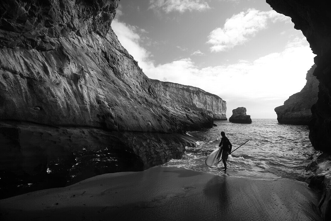 A stand up paddleboarder on the rough coastline north of Santa Cruz.