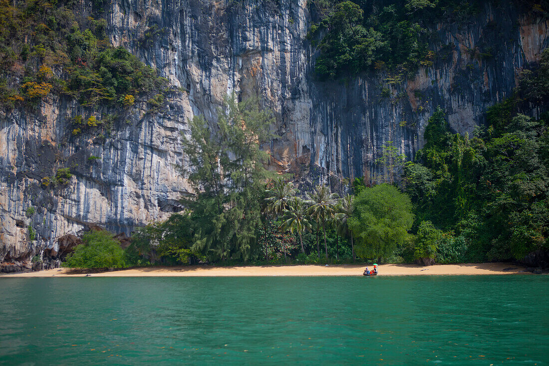 Limestone cliffs loom over a remote beach in Thailand.