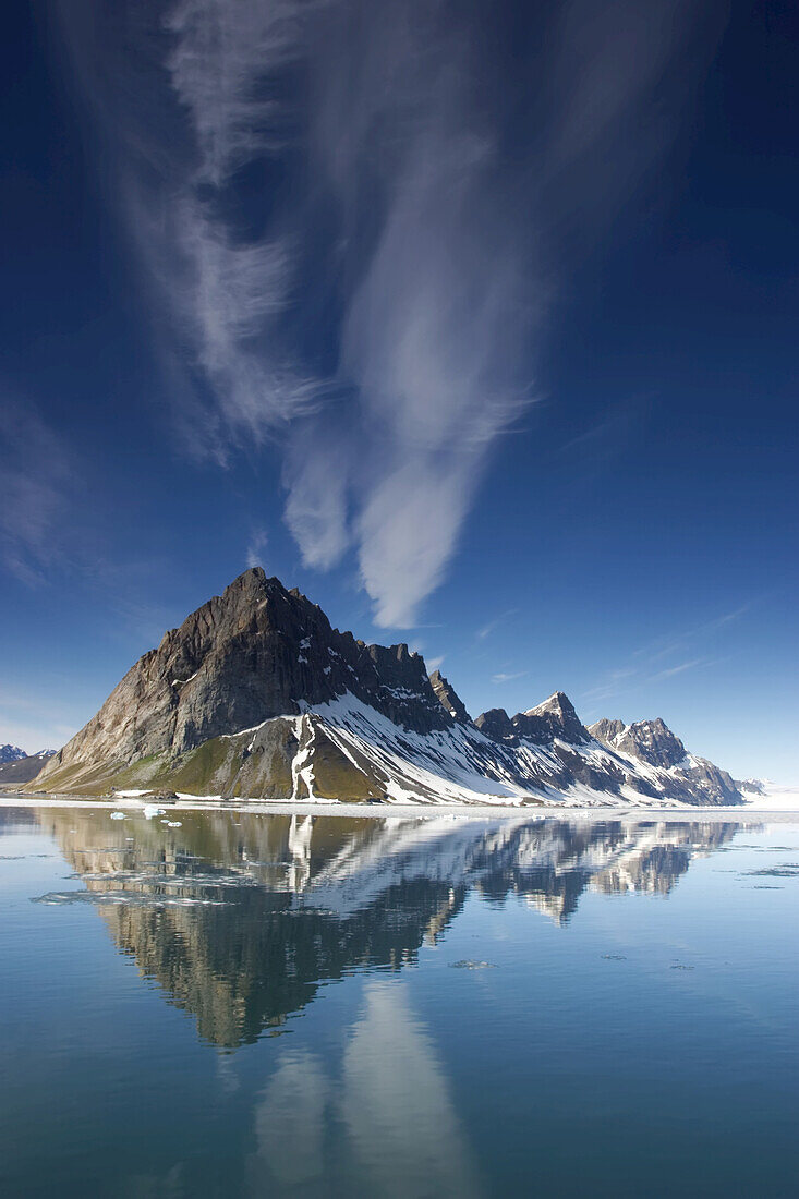Clouds and jagged mountains are reflected in Hornsund Fjord.