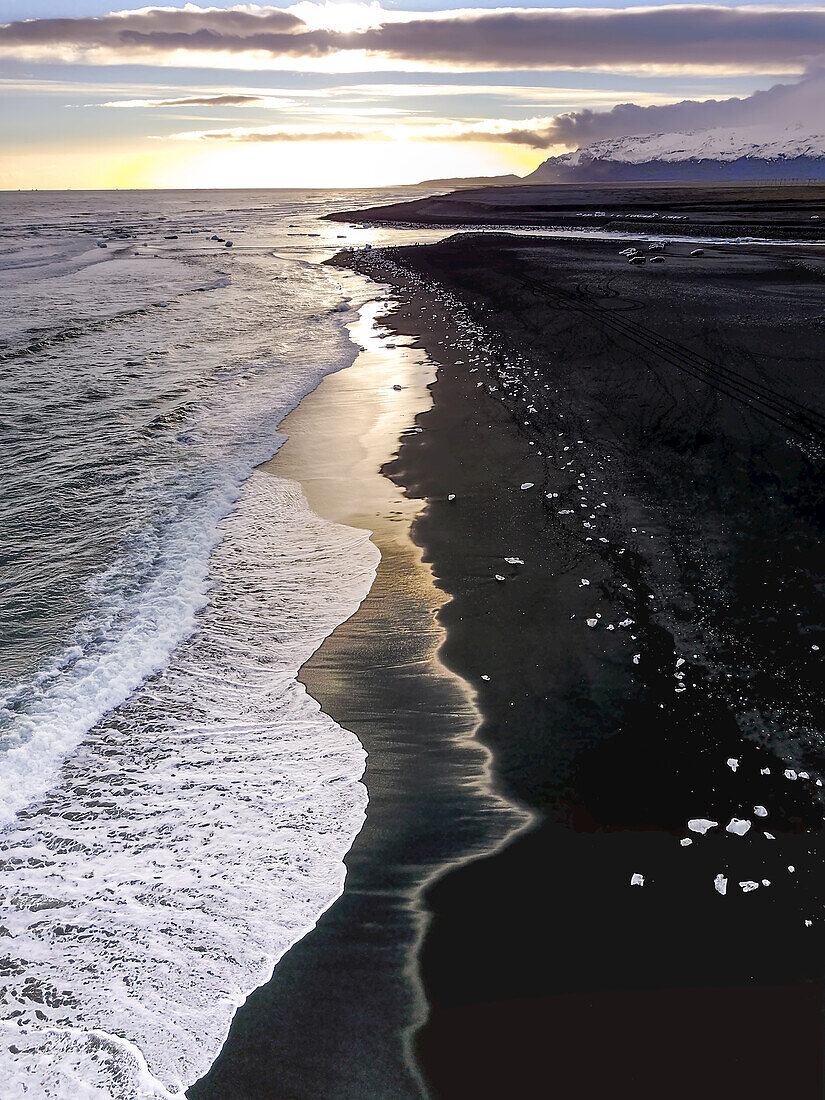 Ein Luftbild der schäumenden Brandung und des Eises aus der Jokulsarlon Gletscherlagune, das an einen schwarzen Sandstrand gespült wird; Jokulsarlon, Vatnaj?l National Park, Island