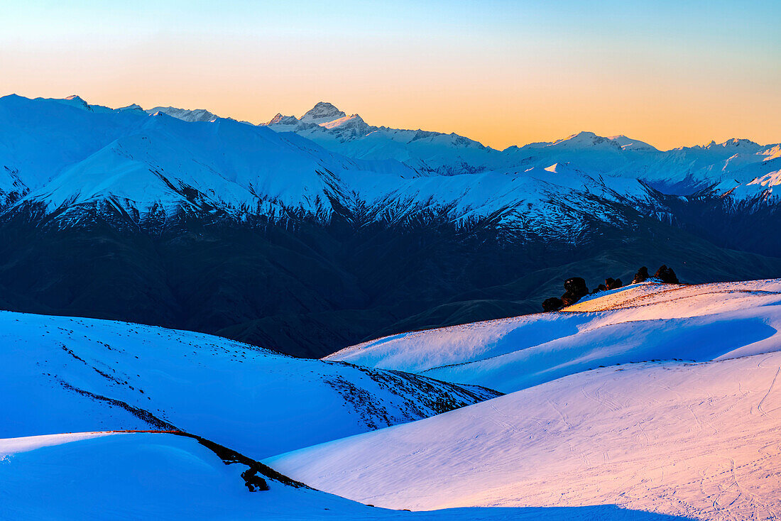Warm light of sunset over the snow-covered alpine peaks of South Island (Te Waipounamu); Wanaka, New Zealand