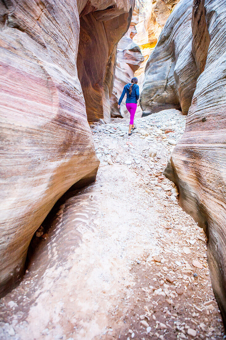 A young woman hiking up a riverbed in search of slot canyons in Zion National Park.