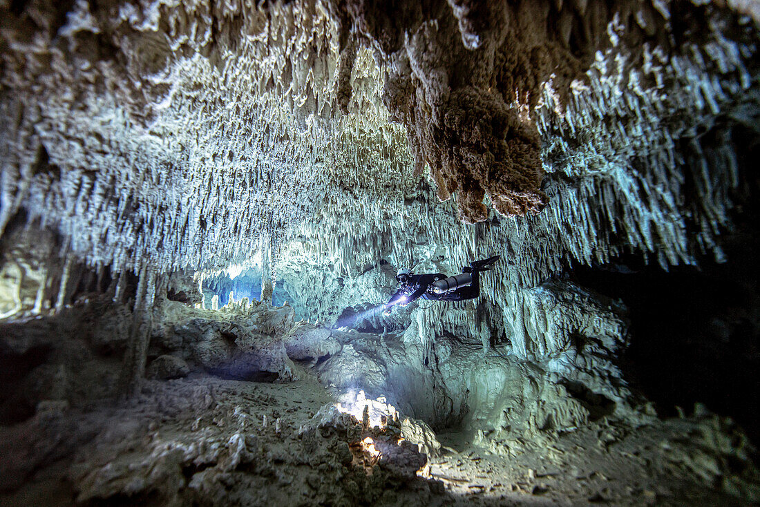 A cave diver passes through a beautiful white section of limestone deep inside of a cave system.