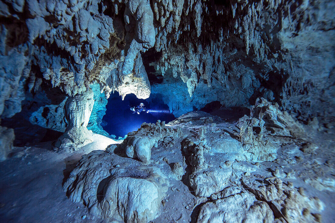 Ein Höhlentaucher durchquert einen schönen weißen Abschnitt aus Kalkstein tief im Inneren eines Höhlensystems.