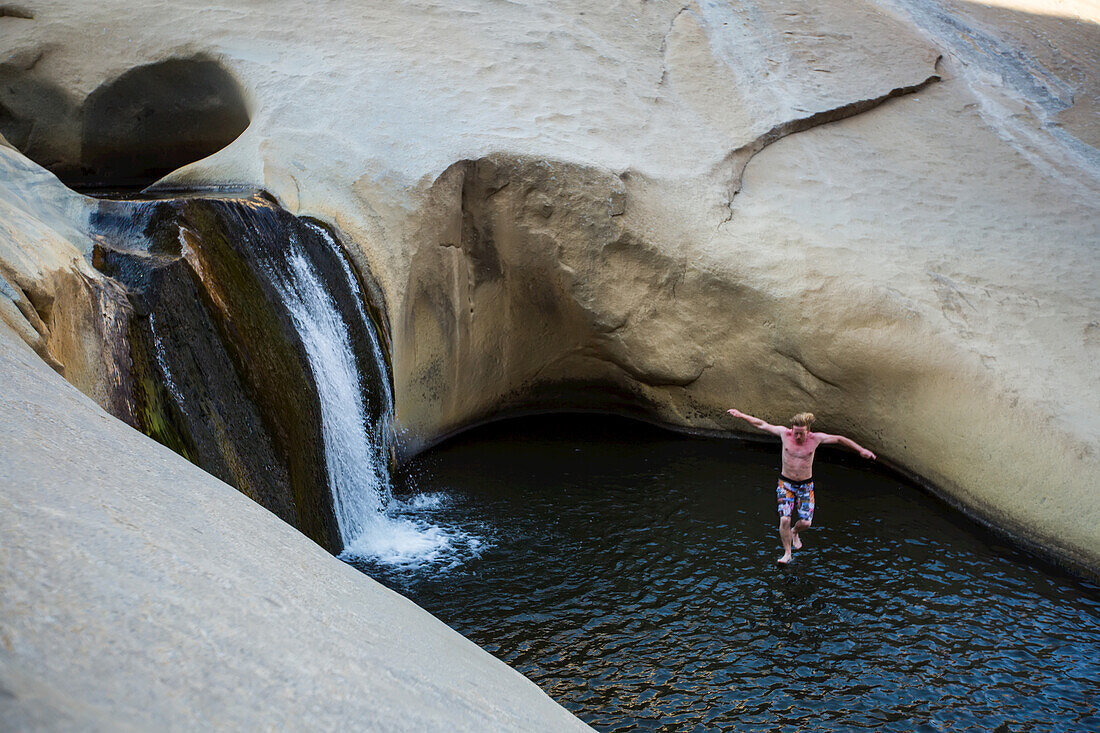 Ein junger Mann springt in einen Pool bei den Seven Teacups in den Bergen der Sierra Nevada.