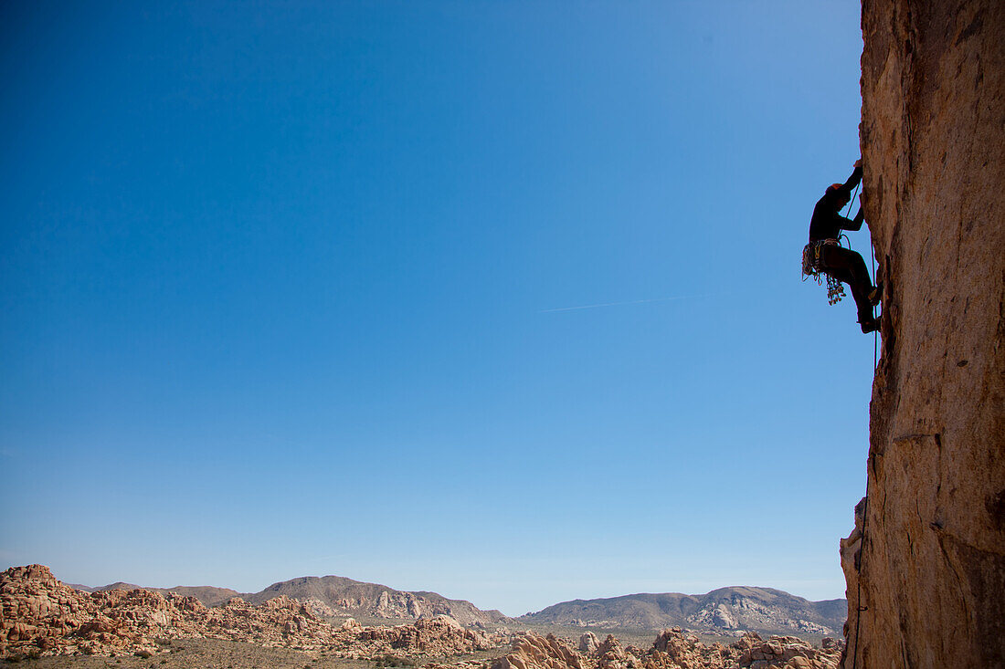 A trad climber ascends a vertical face.