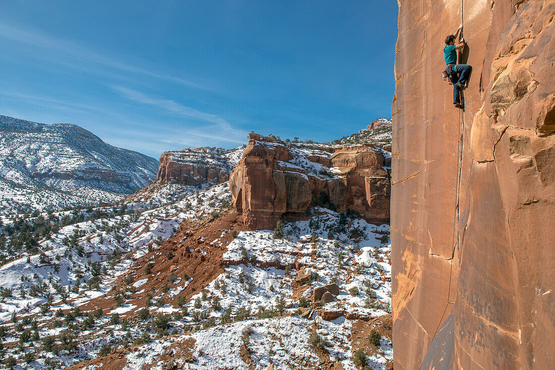 A man climbs sandstone cracks in the Colorado desert.