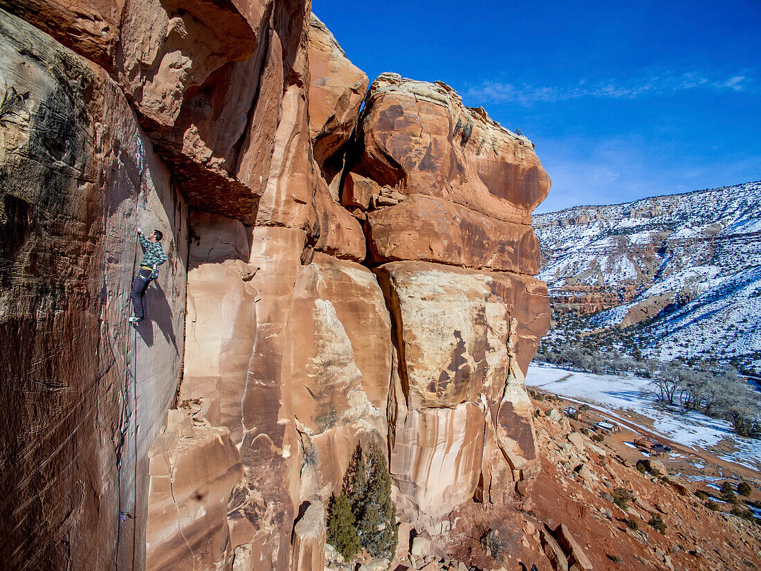 Man climbing sandstone cracks in the Colorado desert.