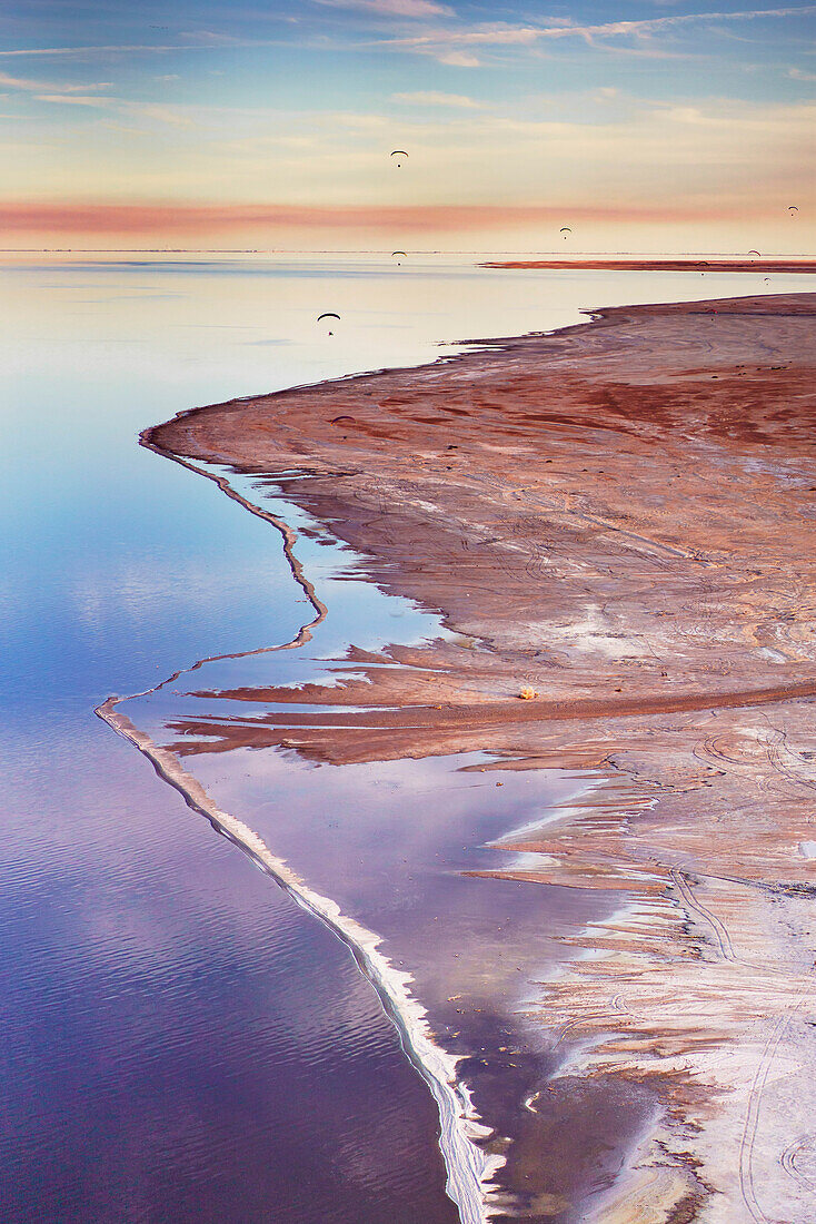Ein Motorschirmflieger fliegt am Ufer des Salton Sea entlang.