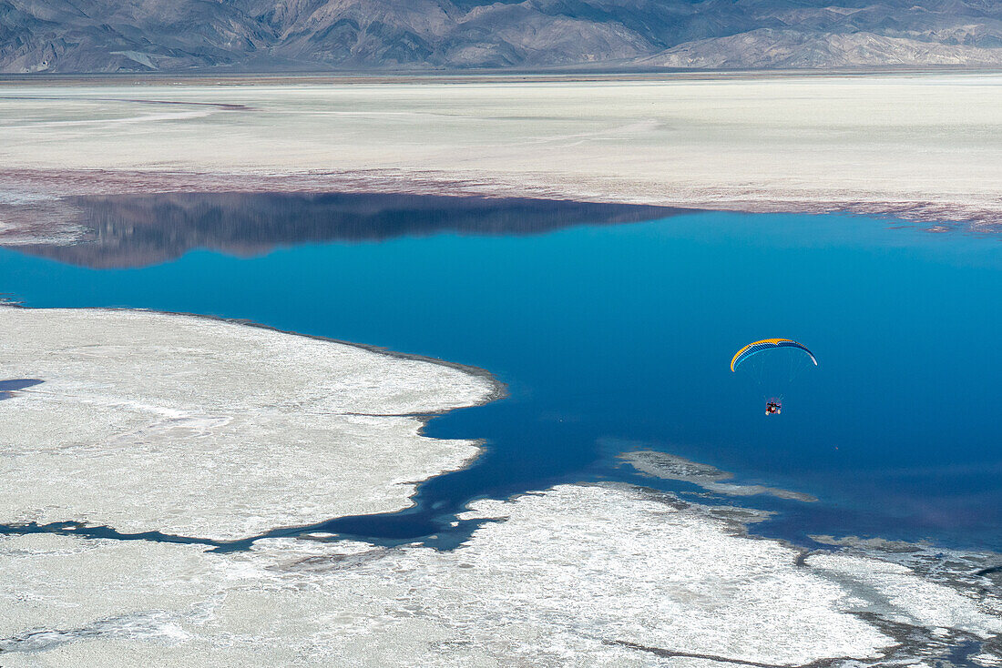 A paramotor pilot flies over Owens Lake, a mostly dry lake bed, in the Sierra Nevada near Lone Pine; Lone Pine, Inyo County, California, United States of America