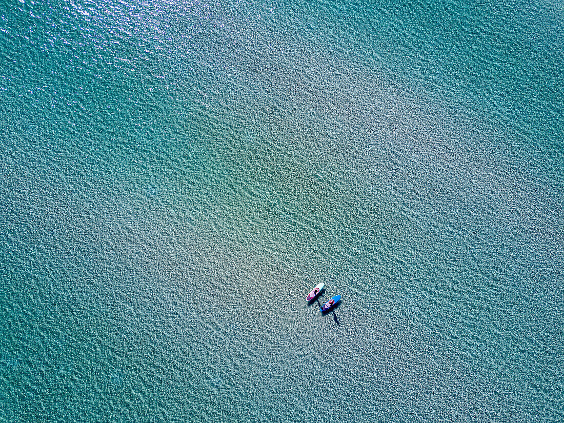 Aerial view of two paddleboarders in Balandra Bay on the turquoise ocean; Baja California Sur, Mexico