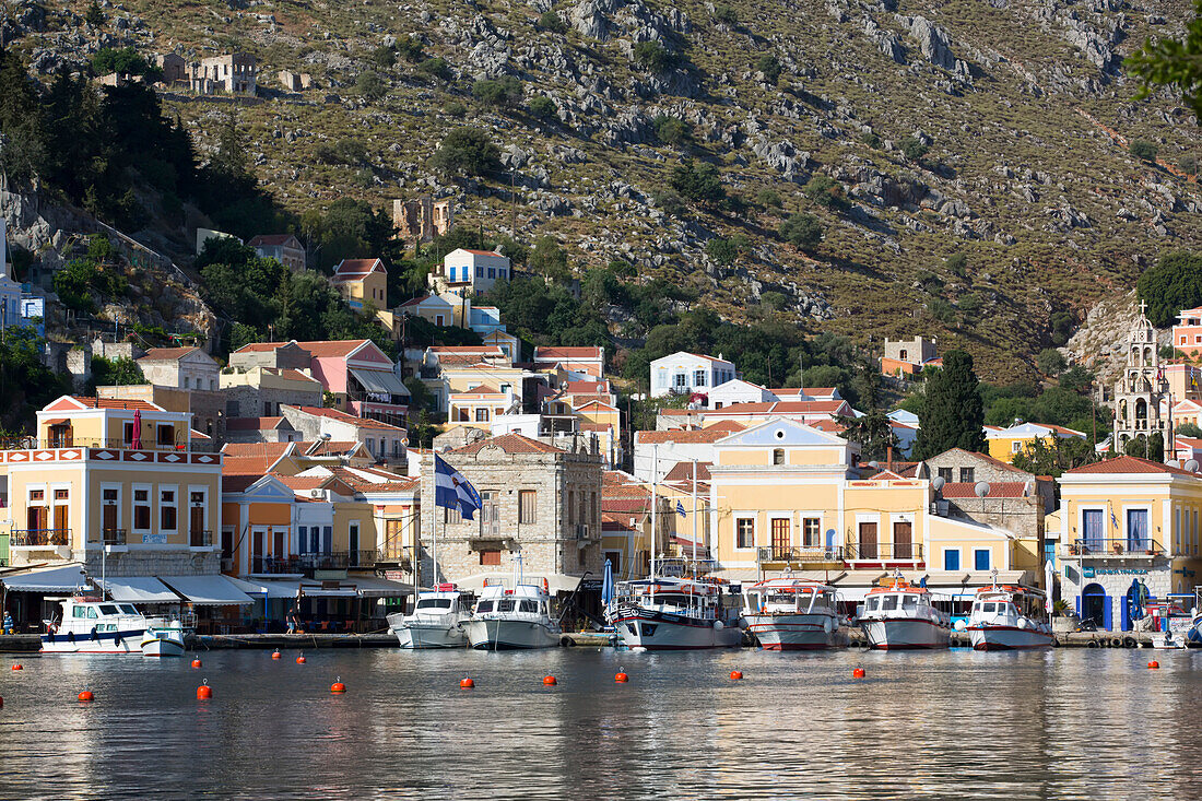Boats moored along the shore at Gialos Harbor, Symi (Simi) Island; Dodecanese Island Group, Greece