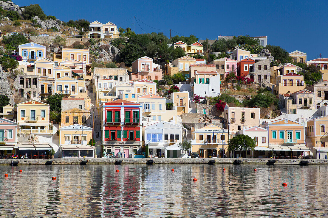 Seedeich und Bojen entlang der Uferpromenade im leeren Yachthafen von Gialos Harbor, Insel Symi (Simi); Dodekanes-Inselgruppe, Griechenland