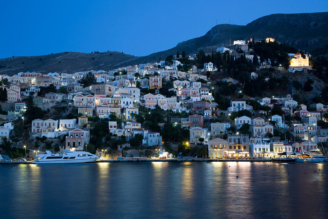 Beleuchtete Gebäude am Hafen von Gialos am Abend, Insel Symi (Simi); Dodekanes-Inselgruppe, Griechenland