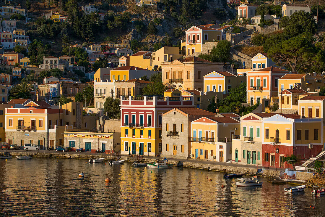 Warm sunlight on the colorful buildings along the waterfront in Gialos Harbor, Symi (Simi) Island; Dodecanese Island Group, Greece
