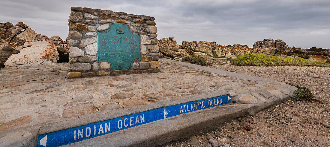 Schild und Metalltafel, die den südlichsten Punkt des afrikanischen Kontinents und die Seegrenze zwischen dem Indischen und dem Atlantischen Ozean am Cape Agulhas anzeigen; Westkap, Südafrika