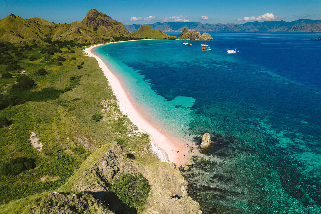 Aerial view of a white sand beach along the shore of Padar Island in Komodo National Park with boats moored off the shore; East Nusa Tenggara, Lesser Sunda Islands, Indonesia