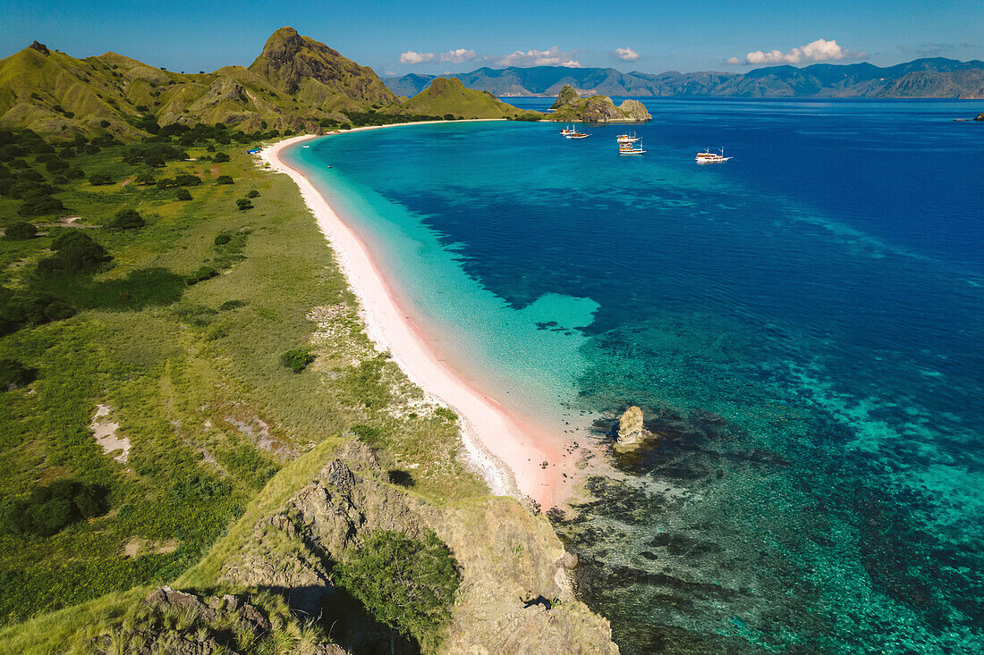 Luftaufnahme eines weißen Sandstrandes entlang der Küste der Insel Padar im Komodo-Nationalpark mit vor der Küste vertäuten Booten; Ost-Nusa Tenggara, Kleine Sunda-Inseln, Indonesien