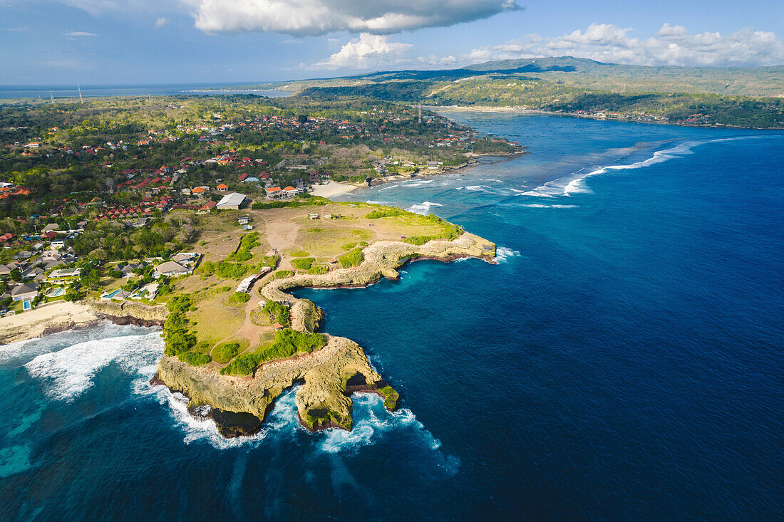 Luftaufnahme von Devil's Tear und der felsigen Küste von Nusa Lembongan mit dem türkisfarbenen Wasser der Bali See, das gegen die Küste bricht; Nusa Islands, Klungkung Regency, Ost Bali, Bali, Indonesien