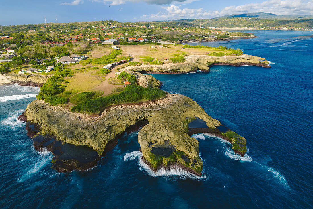 Nahaufnahme, Luftaufnahme von Devil's Tear und der felsigen Küste von Nusa Lembongan mit dem türkisfarbenen Wasser der Bali See, das gegen die Küste bricht; Nusa Inseln, Klungkung Regency, Ost Bali, Bali, Indonesien