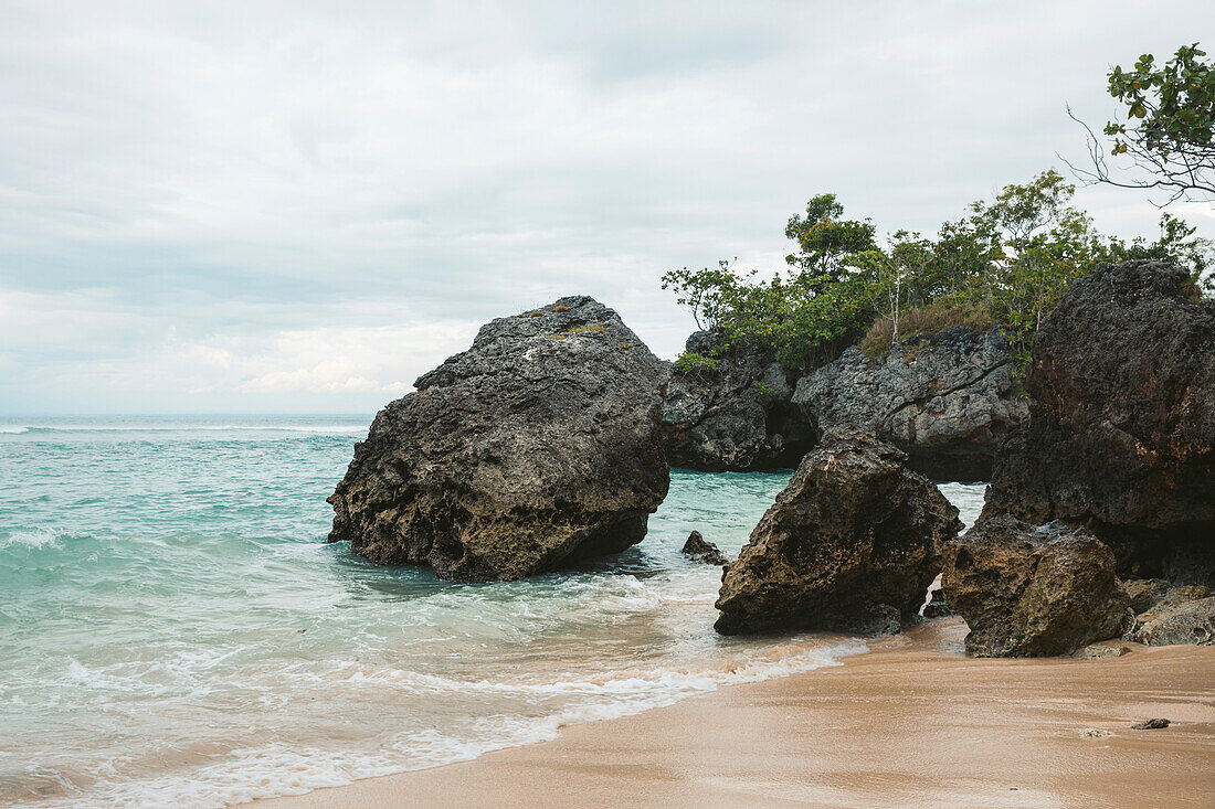 Große Felsformationen am Strand entlang der Bukit Halbinsel am Uluwatu Strand, mit Blick auf den Indischen Ozean in Süd Bali an einem bewölkten Tag; Uluwatu, Badung, Bali, Indonesien