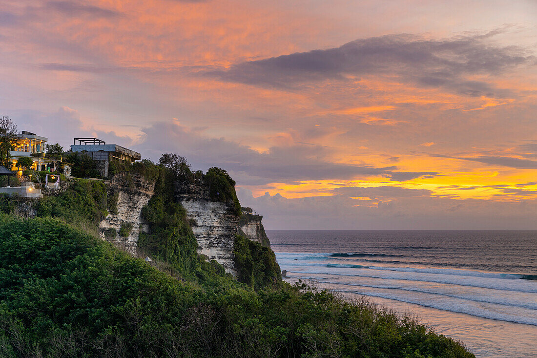 Strandhäuser am Meer auf den Klippen der Bukit-Halbinsel am Uluwatu-Strand, mit Blick auf den Indischen Ozean in Südbali bei Sonnenuntergang; Uluwatu, Badung, Bali, Indonesien