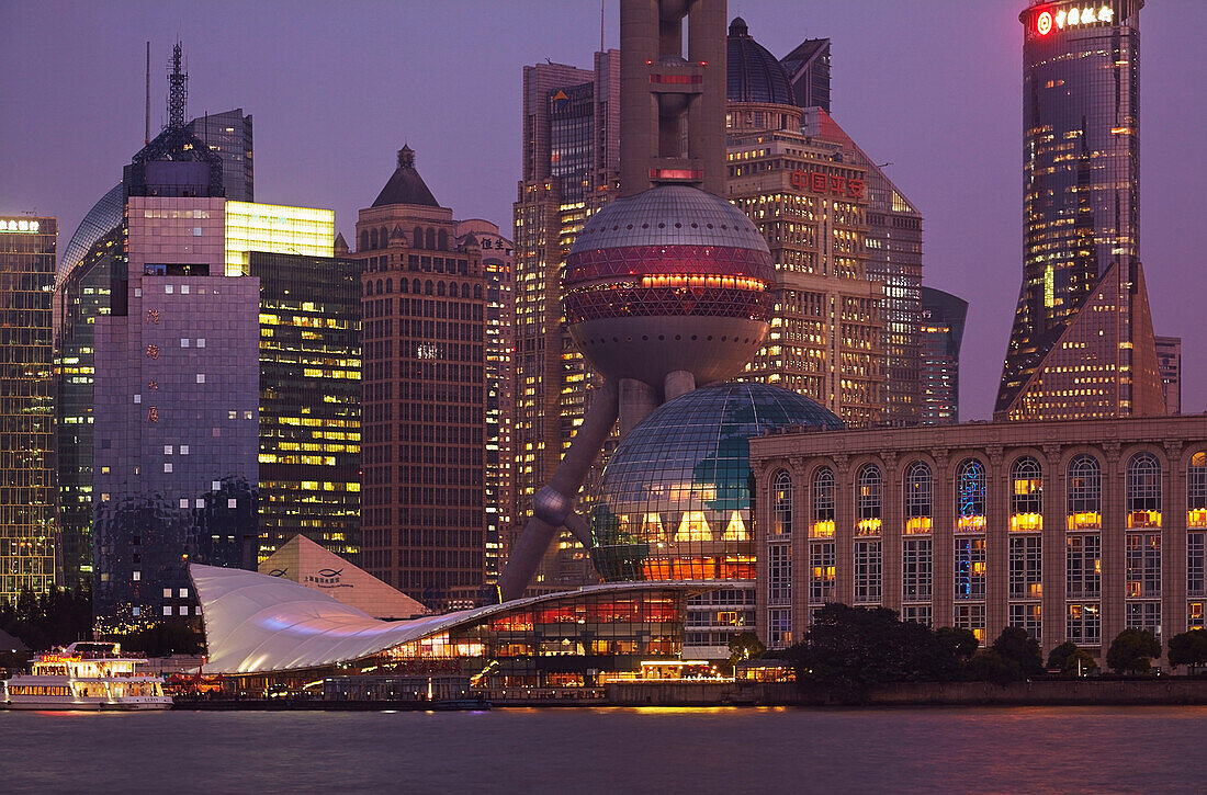 Pudong at dusk, including the Oriental Pearl TV Tower, seen from across the Huangpu River, on the Bund, Shanghai, China.; Pudong, seen from across the Huangpu River, Shanghai, China.
