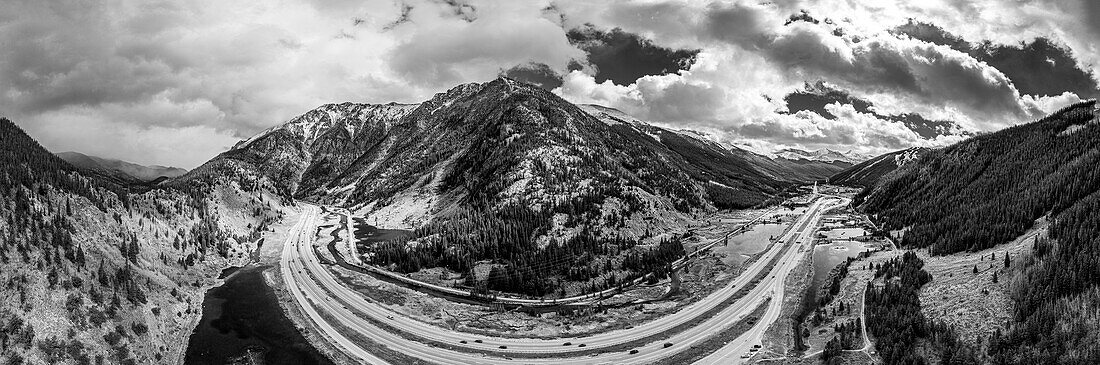 Highway Interstate 70 kurvt durch eine Berglandschaft unter bewölktem Himmel in Colorado, USA; Vereinigte Staaten von Amerika