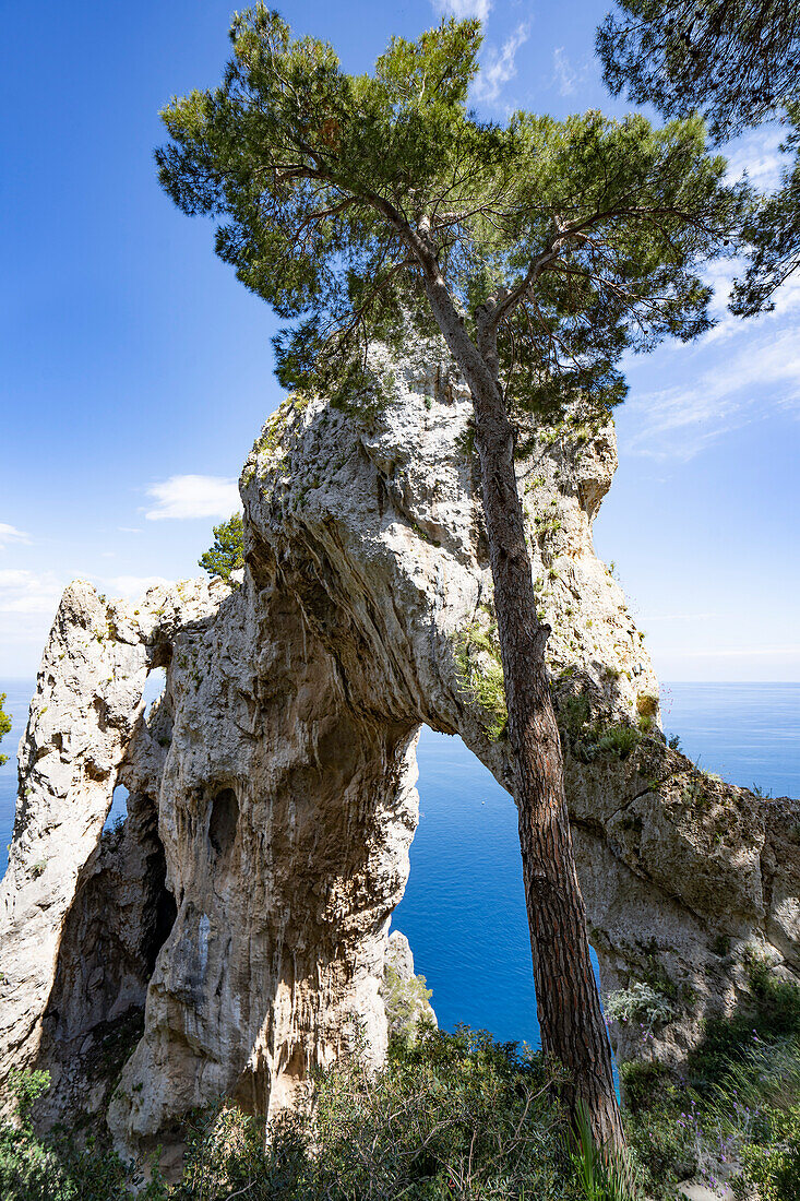 View through the Arco Naturale, a Palaeolithic era limestone arch, remains of a collapsed grotto, 18m high, span of 12m, on the east coast of the Island of Capri; Naples, Capri, Italy