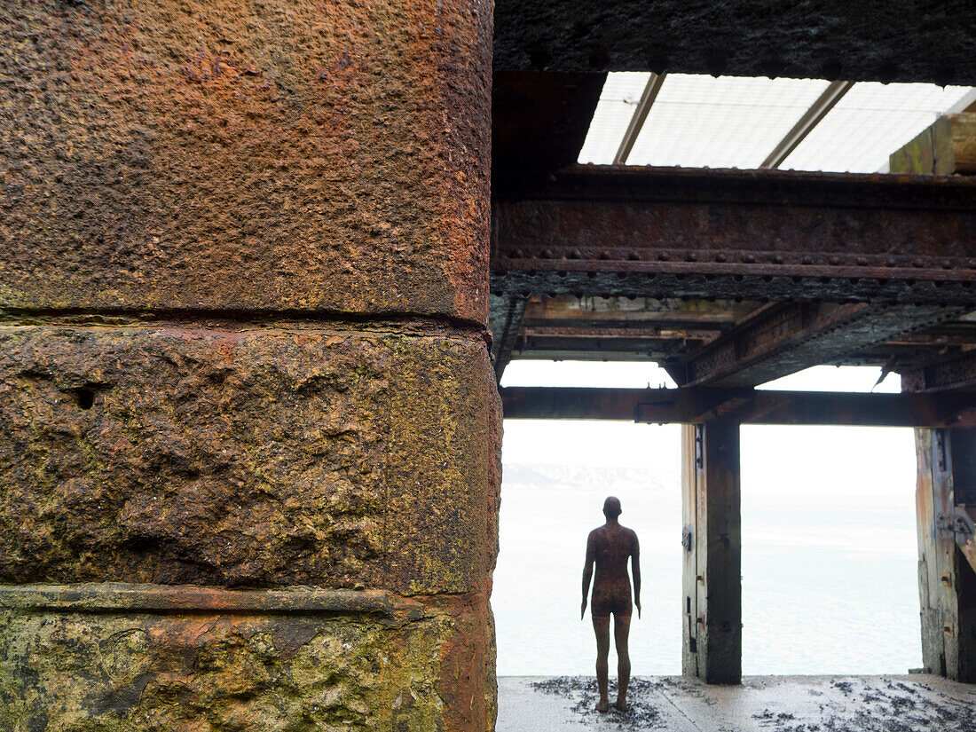 View taken from behind of Antony Gormley's Another Time 1999-2013, cast iron figure, Folkestone Harbour Arm; Folkestone, Kent, England, United Kingdom