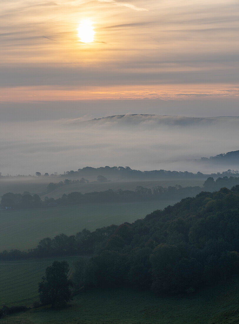 Bank of fog flows over the Long Man of Wilmington in the South Downs National Park at sunrise; Brighton, East Sussex, England