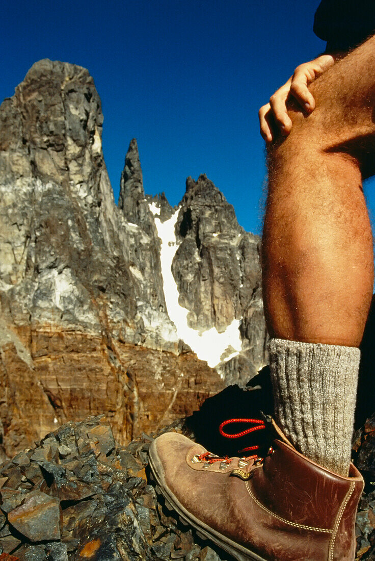 Das Bein eines Wanderers während einer Pause am Fuße eines Granitgipfels in den Anden; Chile.
