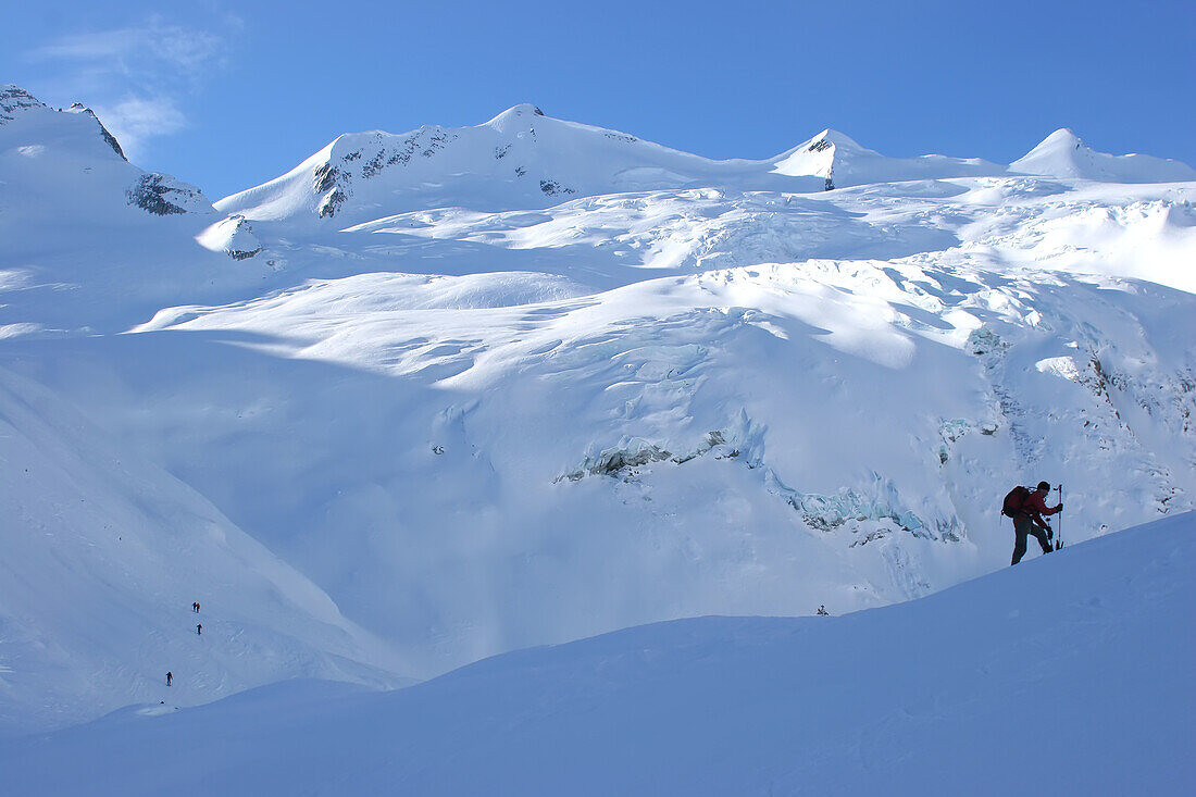 Ein Snowboarder im Gelände und ein Gletscher; Selkirk Mountains, British Columbia, Kanada.