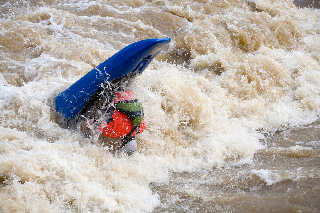Kayker flips over while paddling through strong river rapids.; Potomac River - Maryland/Virginia, USA