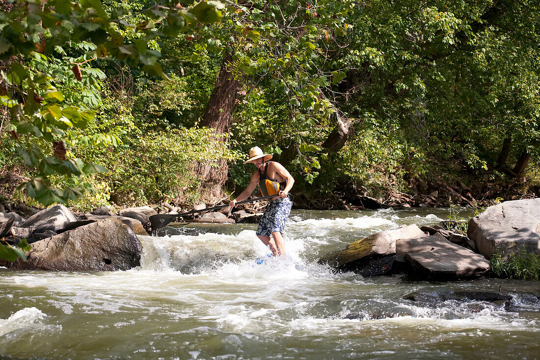 Ein Mann auf einem Stand Up Paddle Board fährt durch Stromschnellen im Potomac River; Bethesda, Maryland.