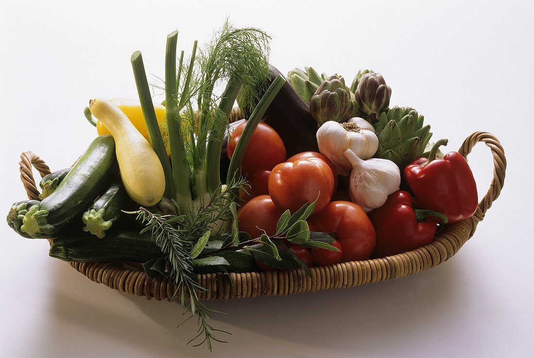 Assorted fresh vegetables and herbs on wicker tray