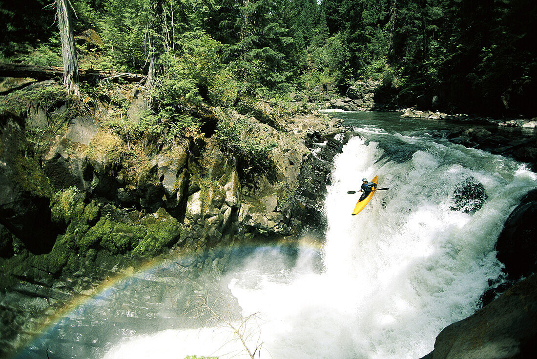 Woman running a big waterfall on the White Salmon River; Upper White Salmon River,Washington State, United States of America