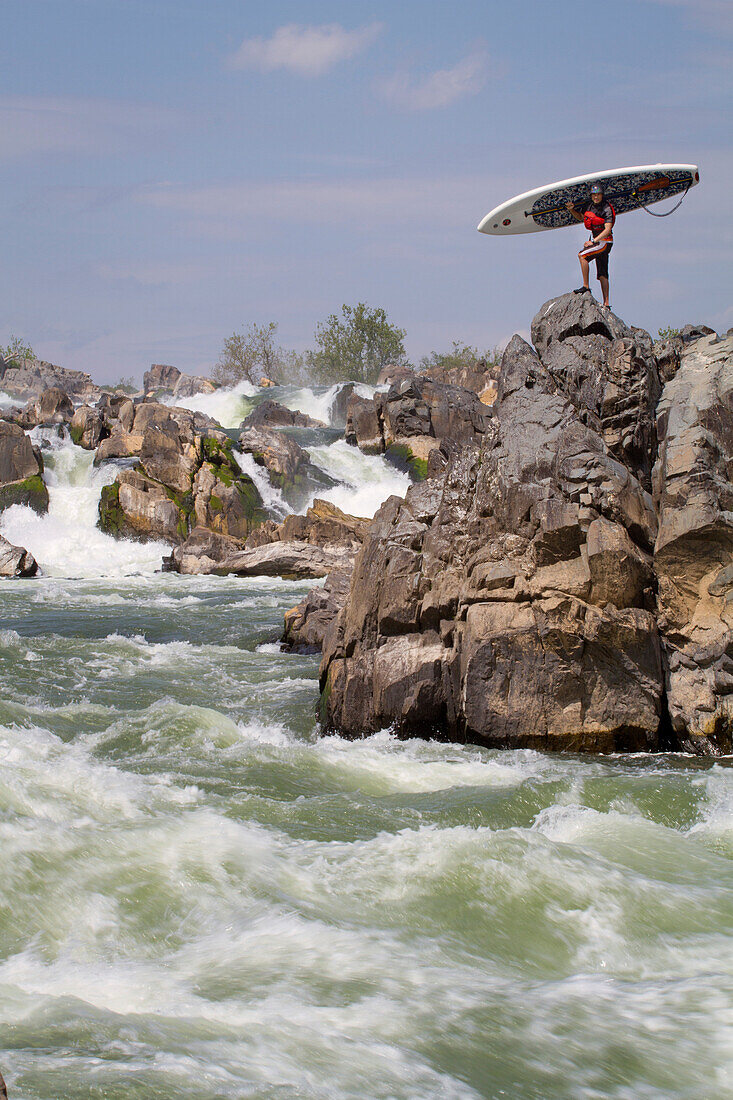 Ein Stand Up Paddle Boarder posiert auf den Felsen unterhalb von Great Falls; Potomac River, Maryland.