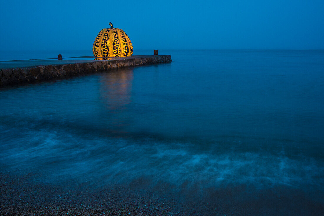 The Naoshima Pumpkin is a sculpture in the form of a giant black and yellow polka-dotted pumpkin by the celebrated artist Yayoi Kusama. It has stood at the end of a pier on the “art island” of Naoshima in the Seto inland sea since 1994.  The sculpture was damaged in a storm in April 2021 and was repaired and reinstalled in  October, 2022; Naoshima Island, Seto Inland Sea, Japan