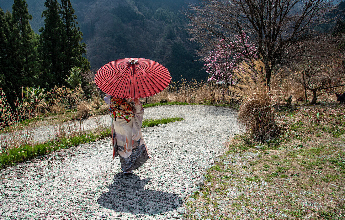 Frau in traditioneller japanischer Kleidung geht eine gewundene Straße im japanischen Iya-Tal auf der Insel Shikoku hinunter; Miyoshi City, Shikoku, Japan