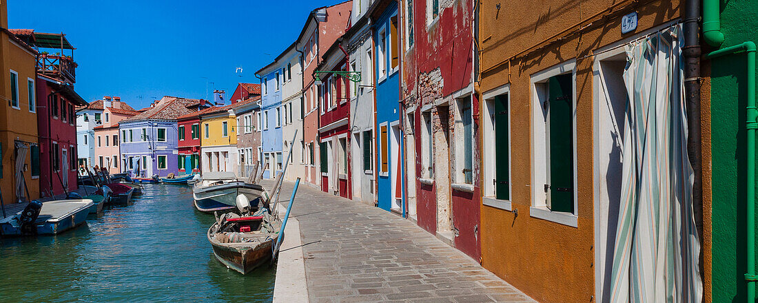 Colorful houses along the waterfront canal on Burano Island in Veneto; Venice, Italy